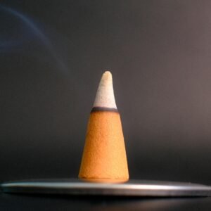 A close-up of a burning incense cone with smoke rising against a dark background, evoking calm and serenity.