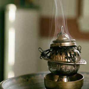A close-up of a decorative metal censer emitting smoke, creating a tranquil atmosphere indoors.